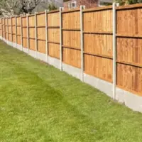 Traditional closeboard featheredge fencing panels with sturdy concrete posts and concrete gravel boards running alongside a vibrant green residential lawn