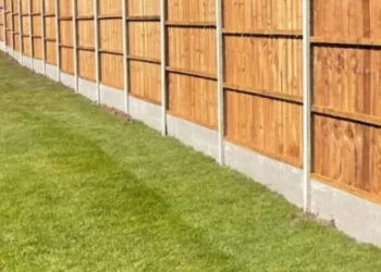 Traditional closeboard featheredge fencing panels with sturdy concrete posts and concrete gravel boards running alongside a vibrant green residential lawn